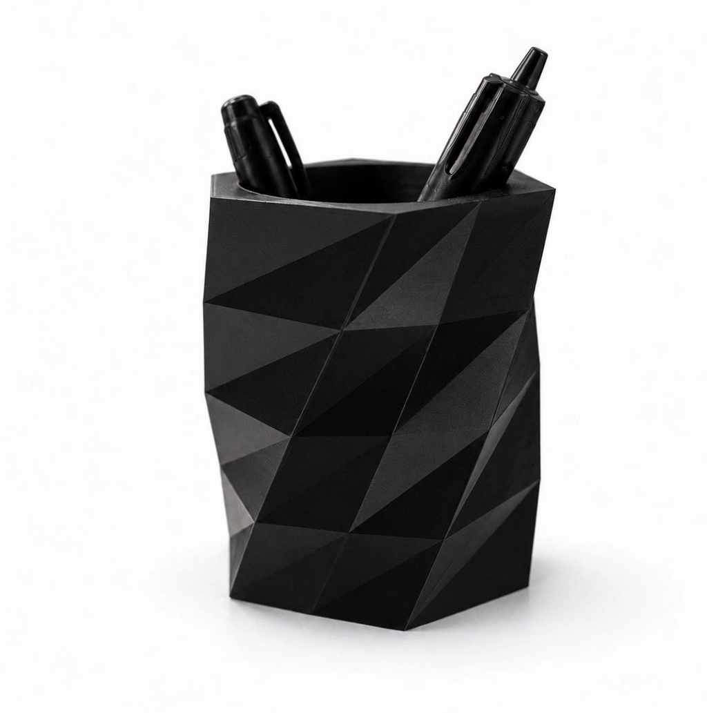Black geometric pen holder with three pens on a white background
