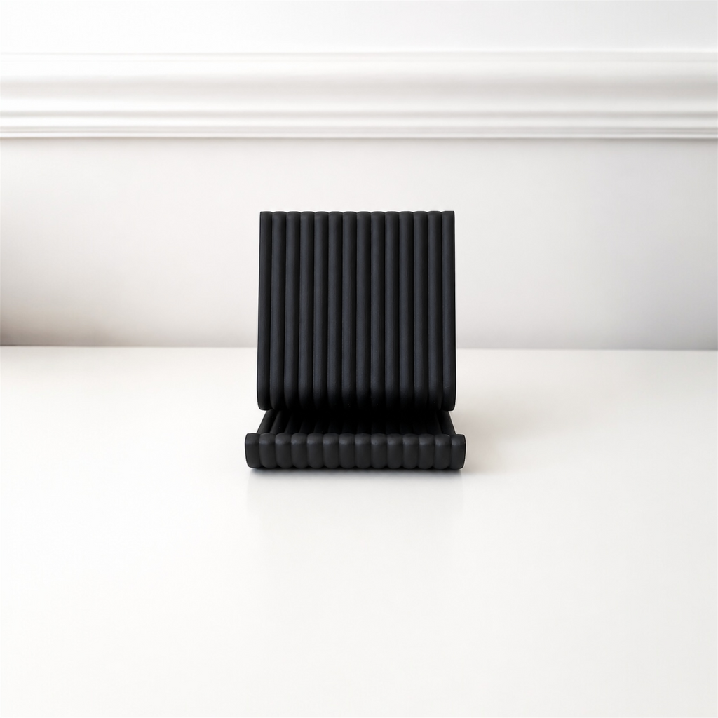 Black pleated object on a white surface with a white background
