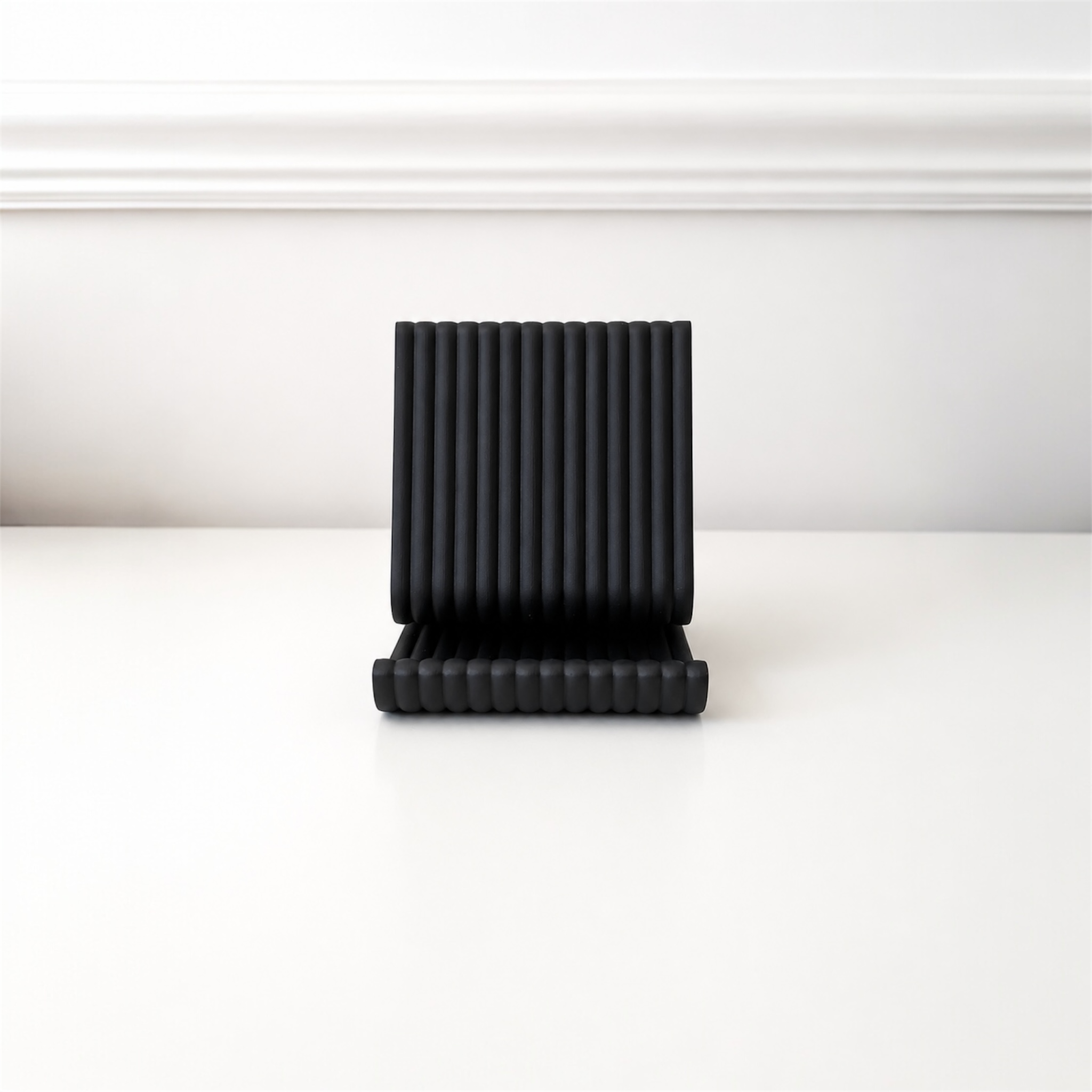 Black pleated object on a white surface with a white background